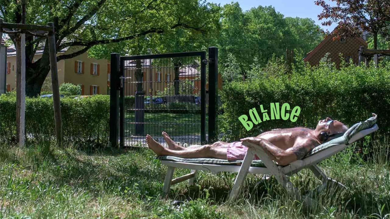 A woman in a wheelchair in her room in sunlight, with the curved word “Lebensmutig” in lilac next to her