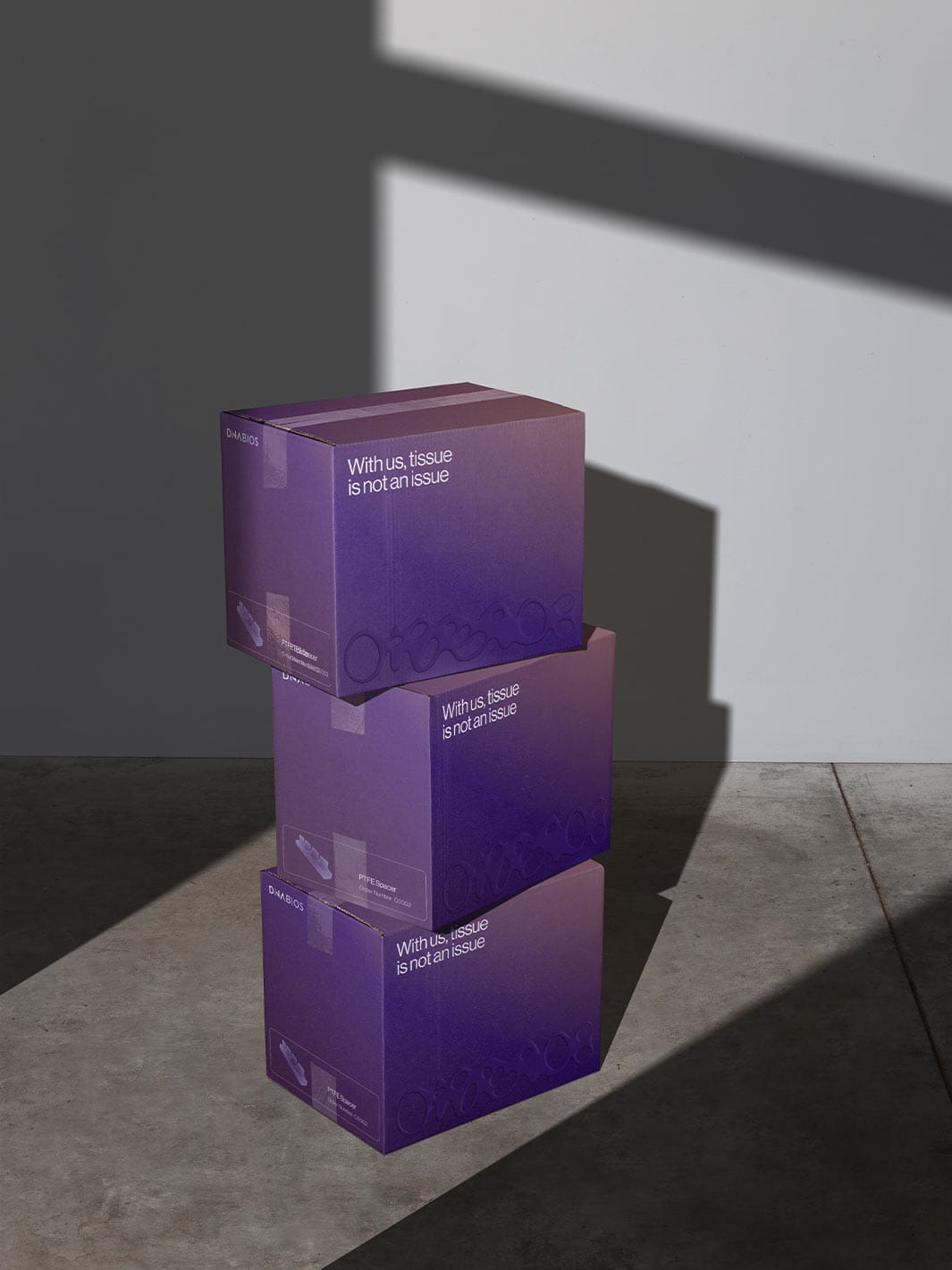 Three stacked violet shipping boxes with the claim “With us, tissue is not an issue” in the shadow of a window