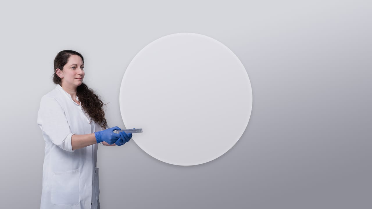 Website mock-up: a researcher in a lab coat holds a sample plate in front of a large round light