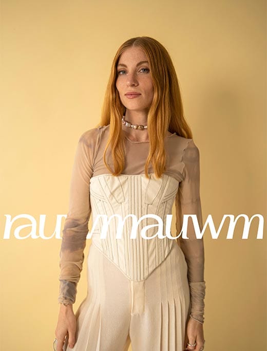 A model in a cream corset in front of a yellow backdrop with the rauwm wordmark