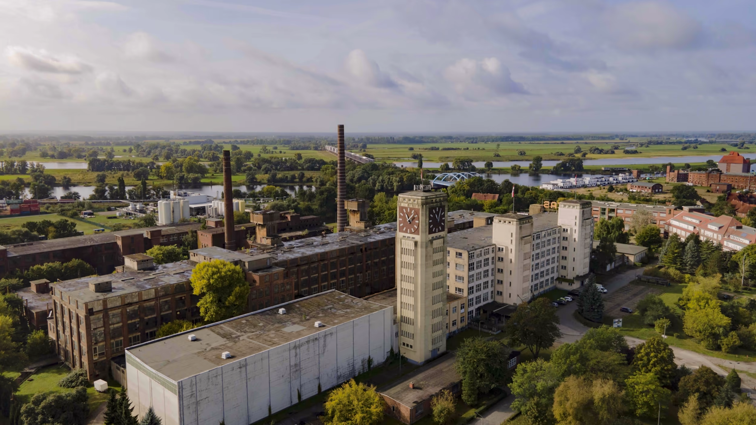 Aerial view of the former VERITAS sewing machine factory in Wittenberge with its clock tower, overlaid with “Space for big ideas” and the VERITAS wordmark