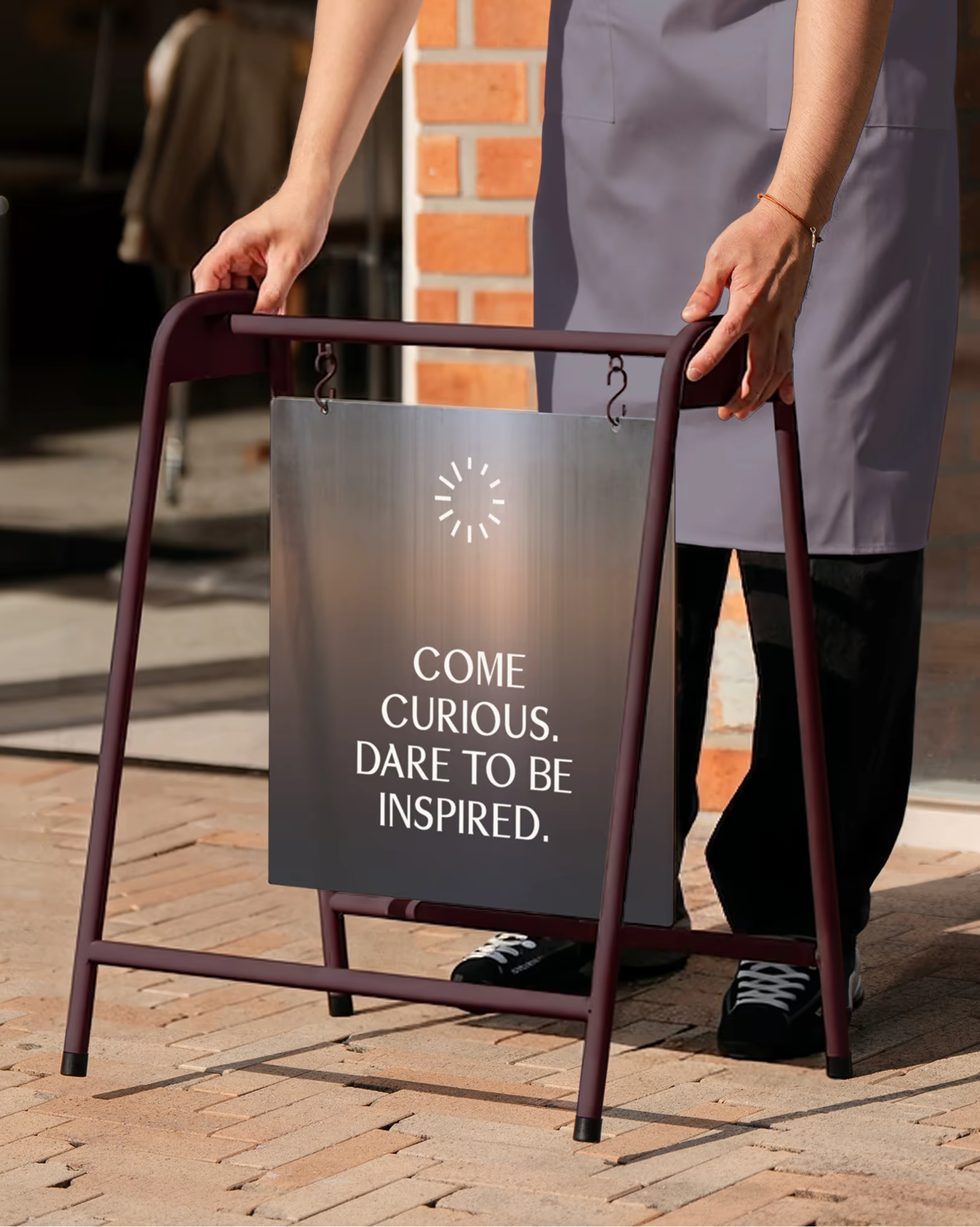 An A-frame sign with the text “Come curious. Dare to be inspired.”