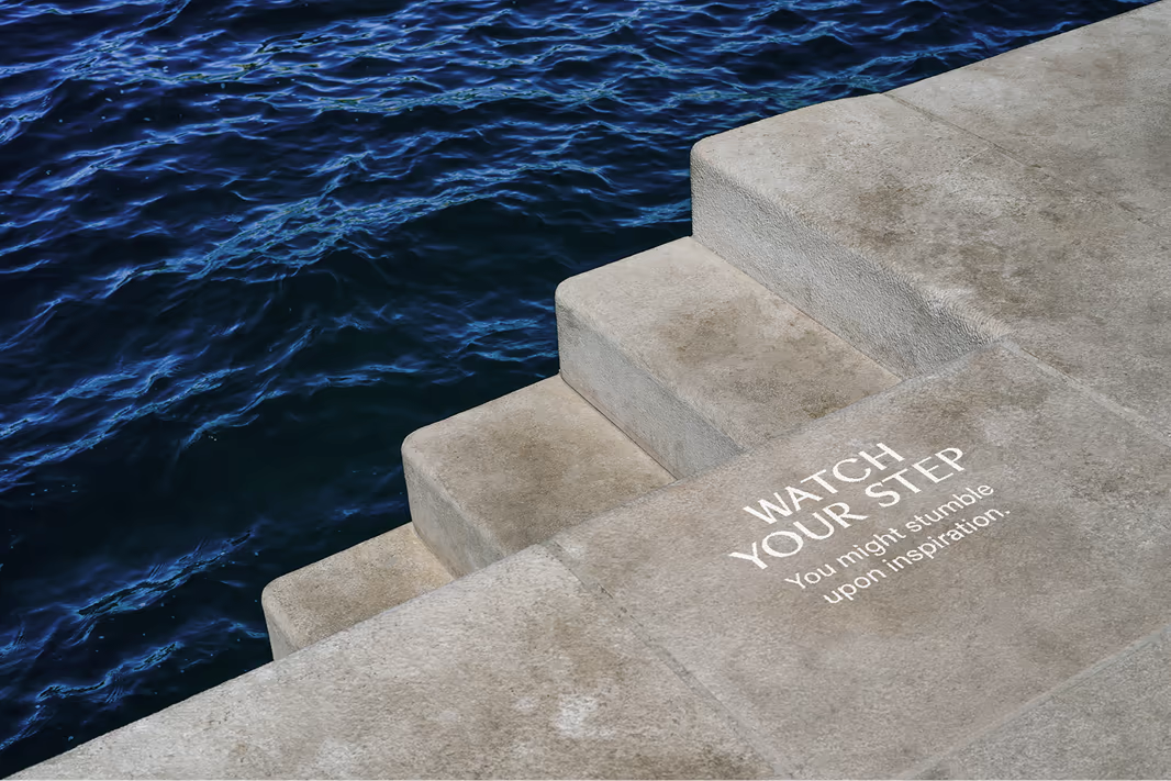 Stone steps at the water with the sign “Watch your step”